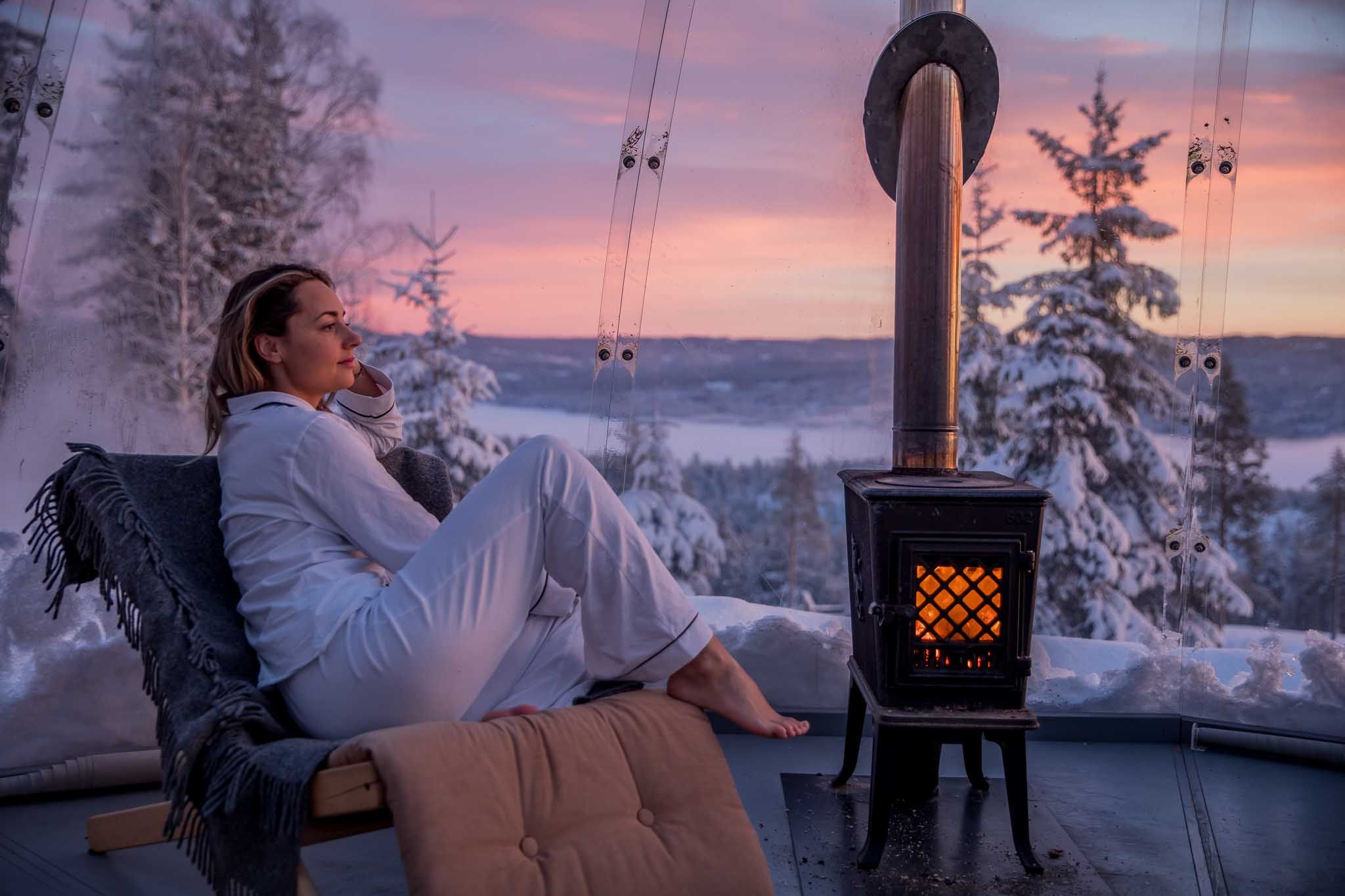 Girl sitting by a wood-burning stove inside the igloo