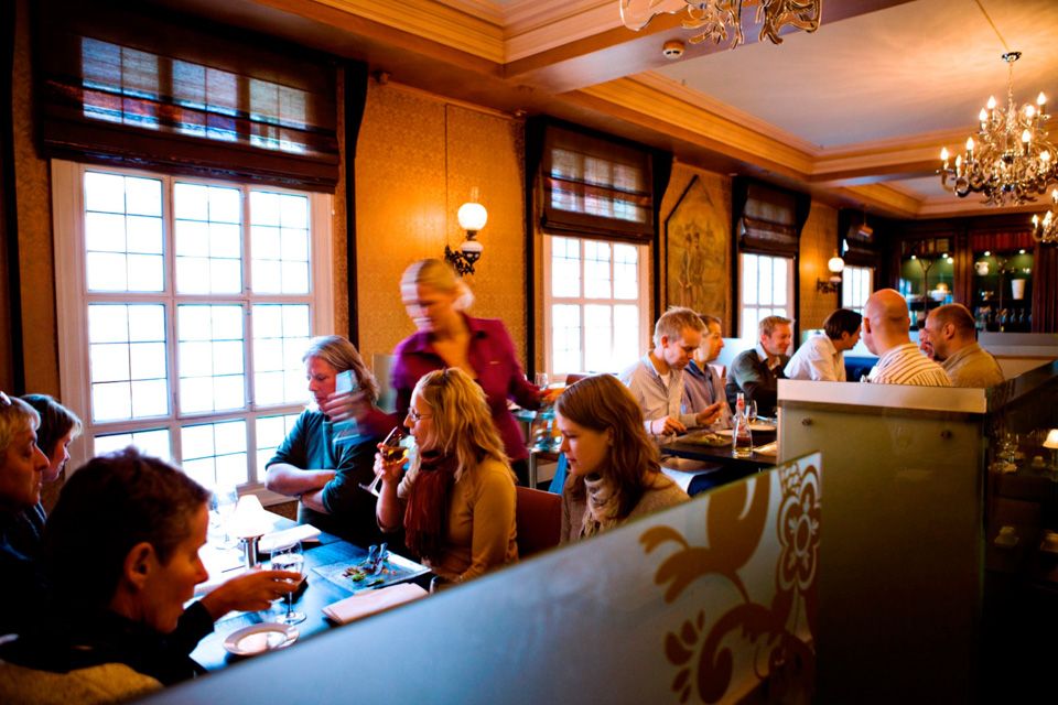 Various tables with seated people eating and drinking.