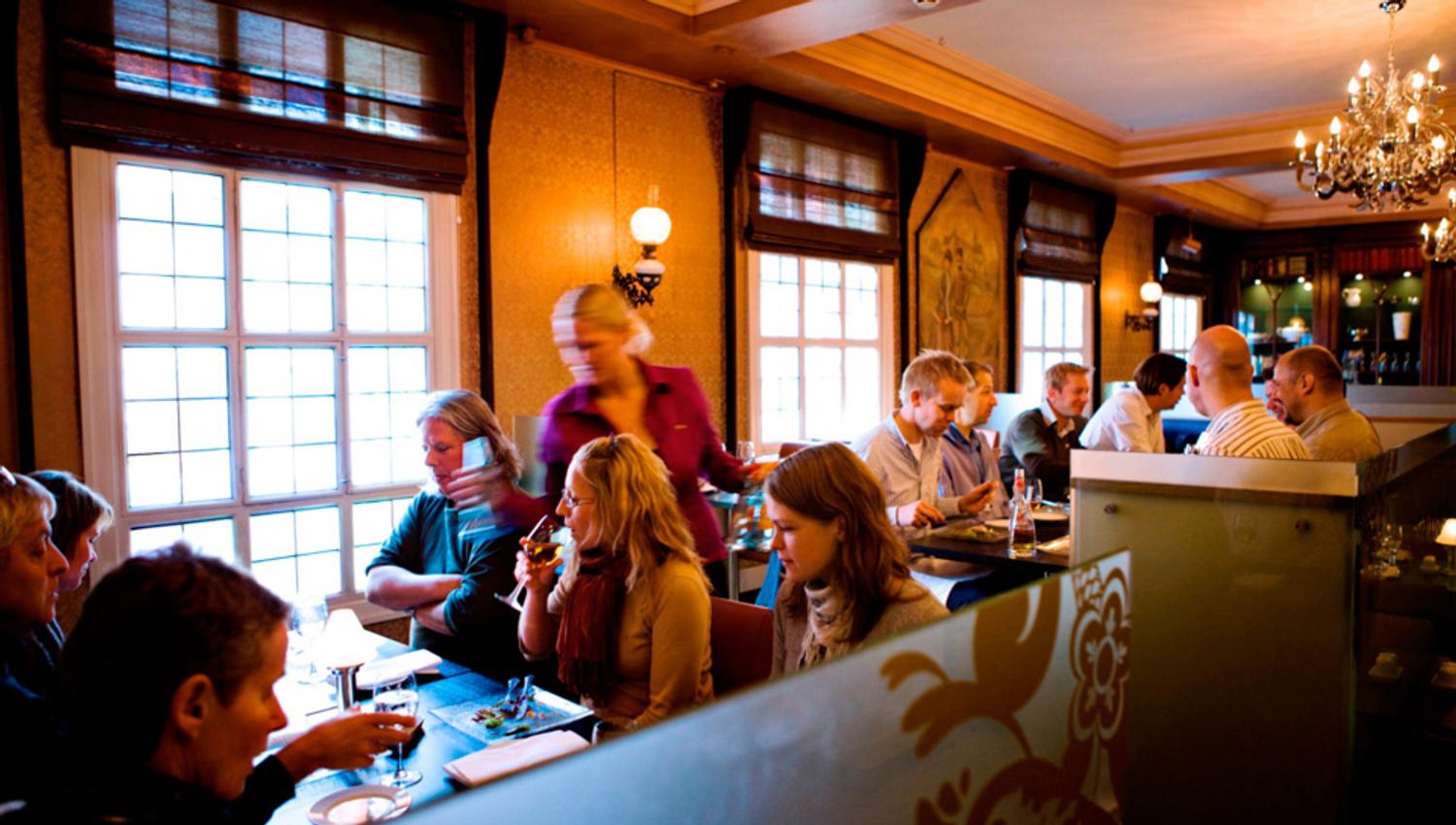 Various tables with seated people eating and drinking.