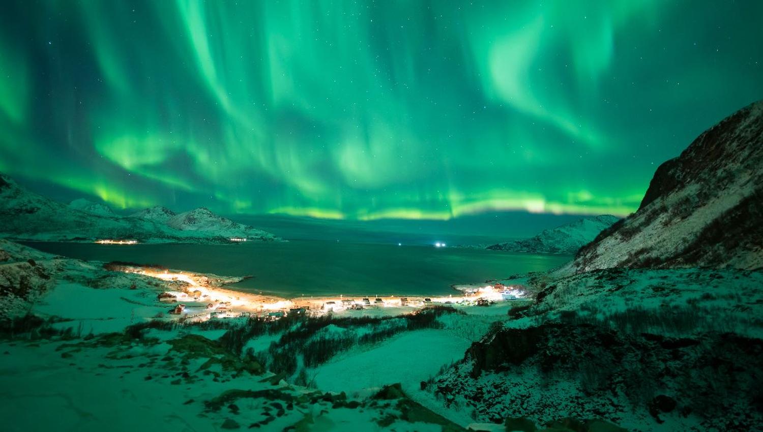The Northern Lights illuminate the mountains and fjords during a guided Northern Lights tour from Tromsø in Northern Norway.