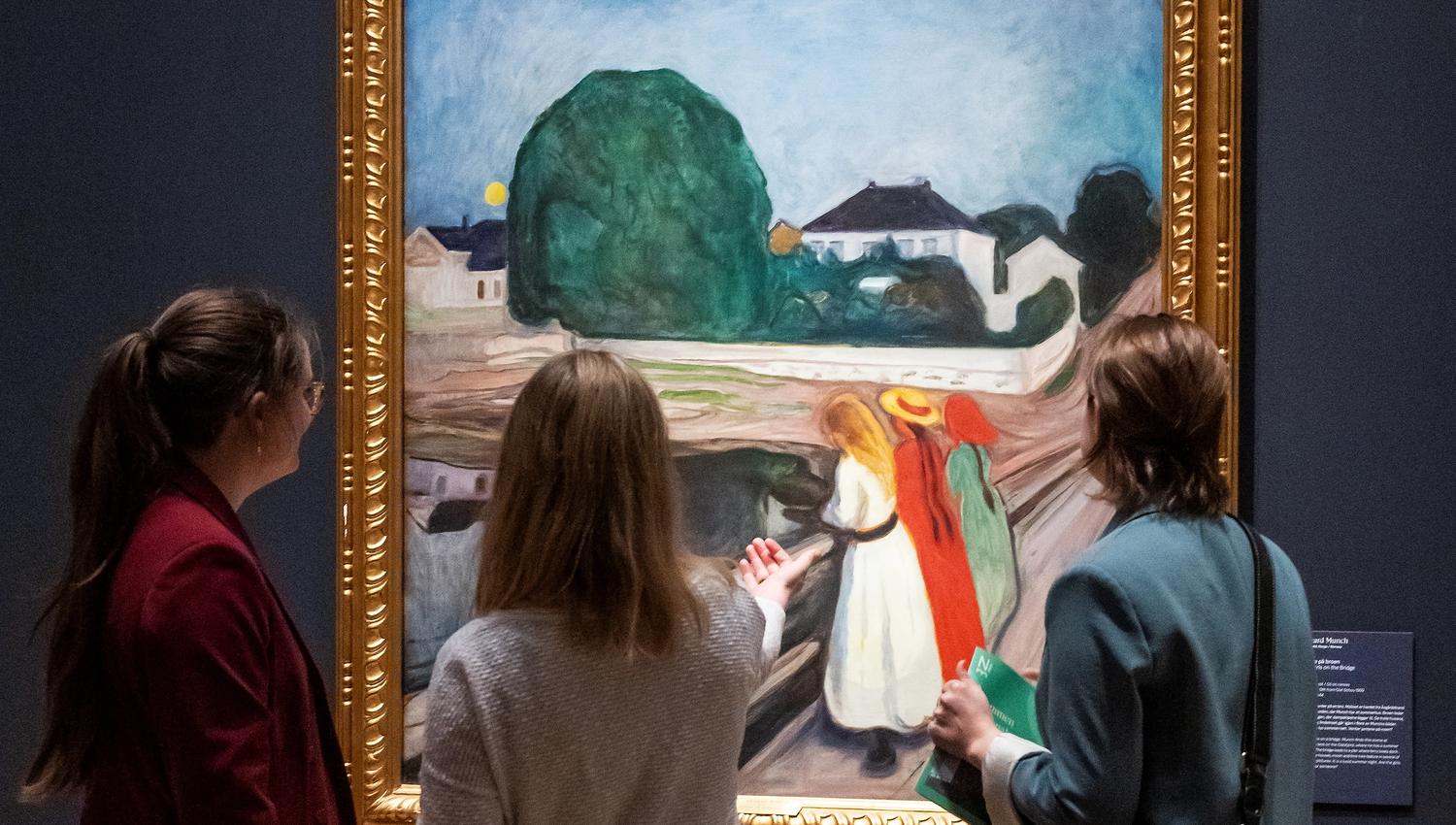 Three girls looking at the painting "Girls on a Bridge" by Edvard Munch.