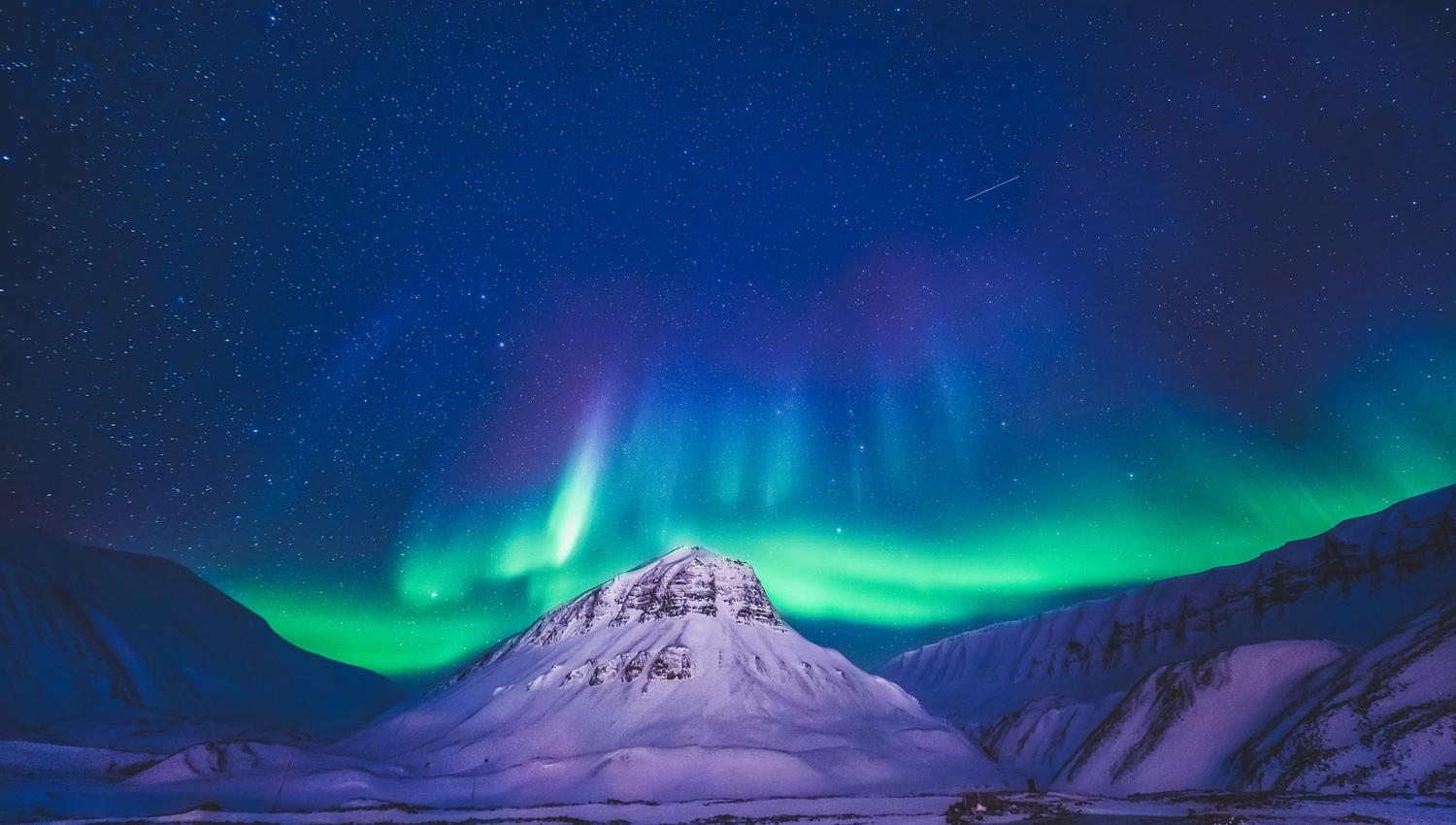 Nordlys danser over en fjelltopp
