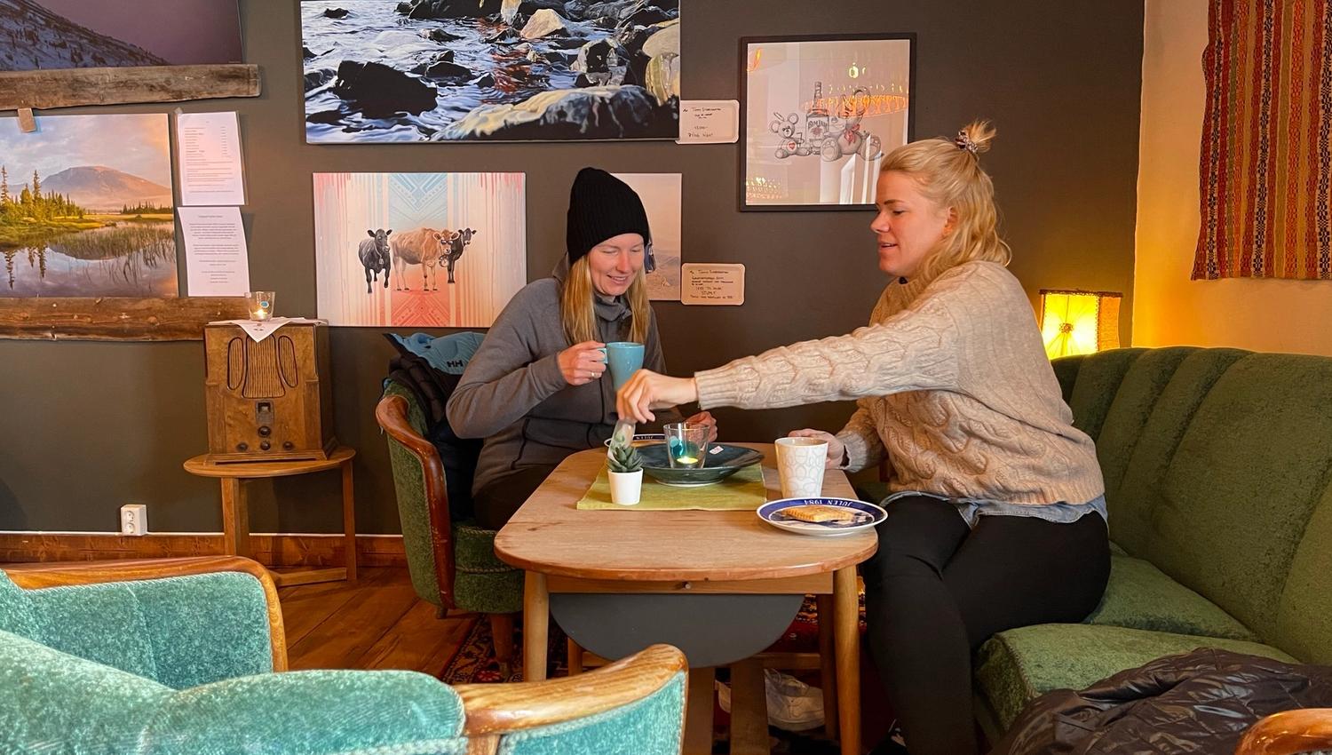 To damer som sitter ned og koser seg med kvikaku og kaffe