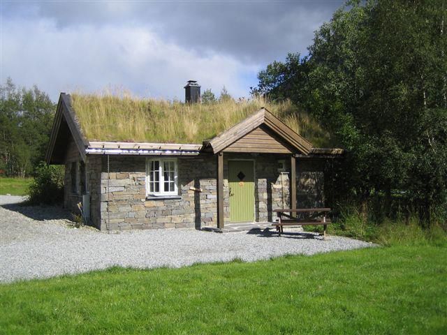 Traditional stone cabin with grass roof at Seim Camping, ideal for an authentic Norwegian stay close to nature.