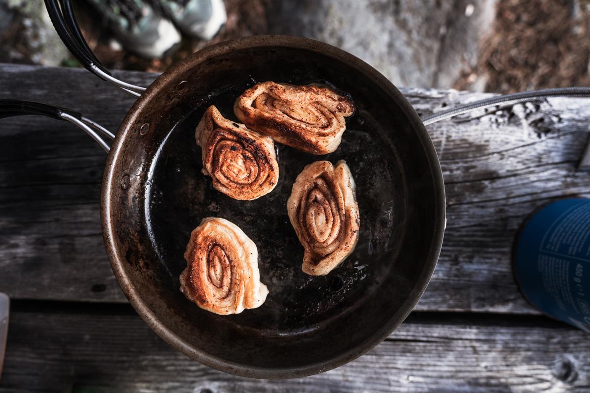 Food frying in a pan on outdoor cooking gear.