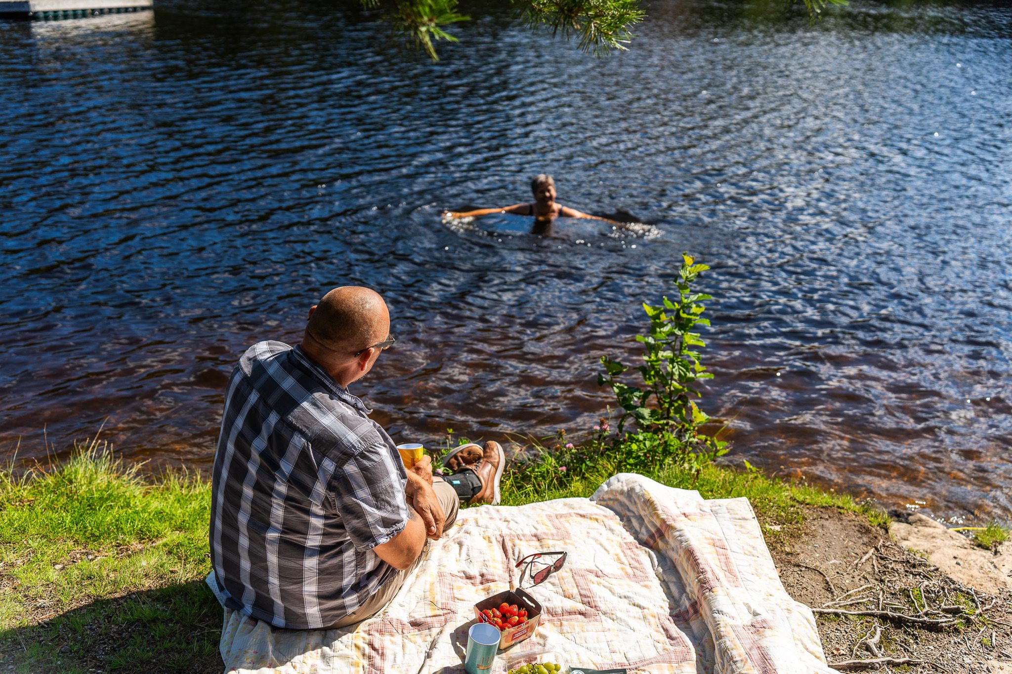 mann sitter på land og ser på noen som bader