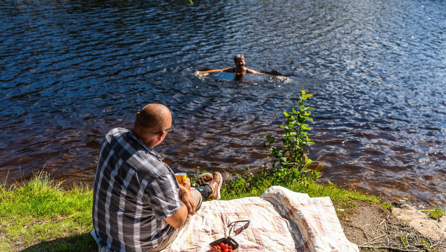 mann sitter på land og ser på noen som bader