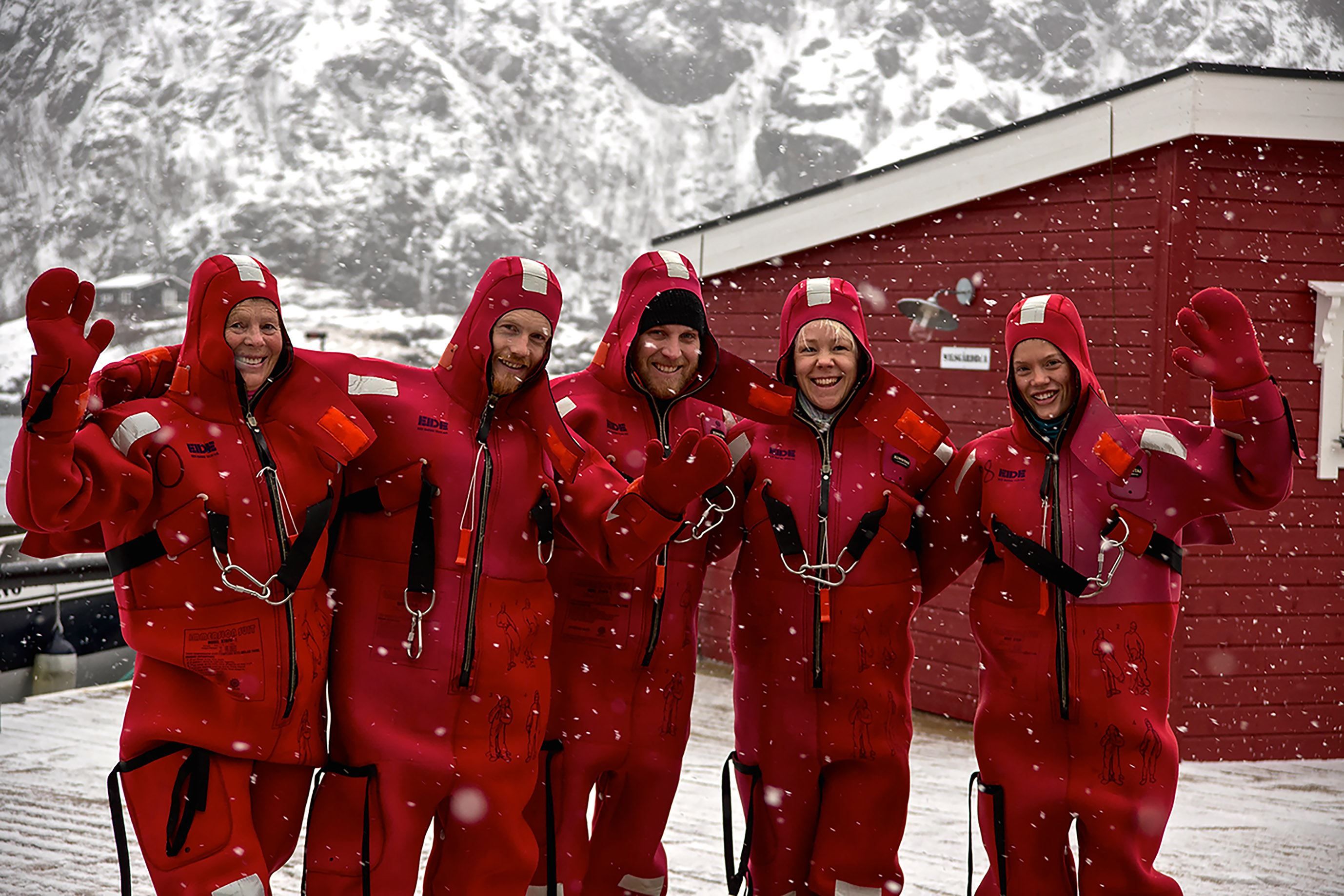 Five people wearing dry suits in snowy weather.