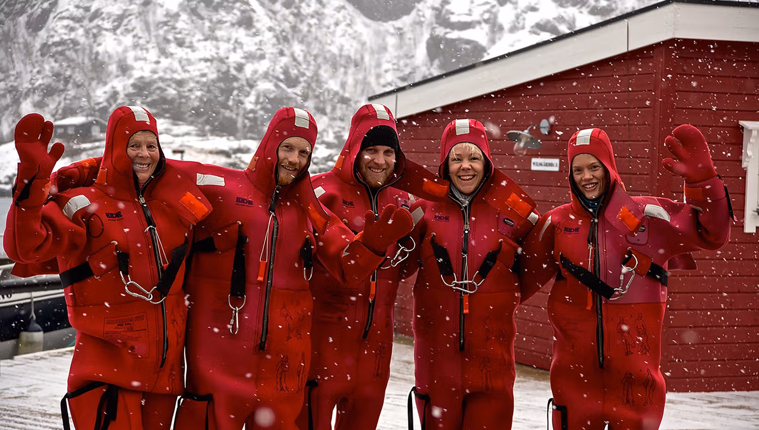 Five people wearing dry suits in snowy weather.