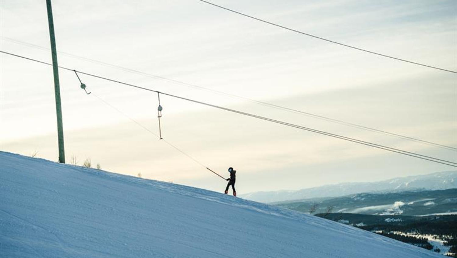 skier uses ski lift up the hill
