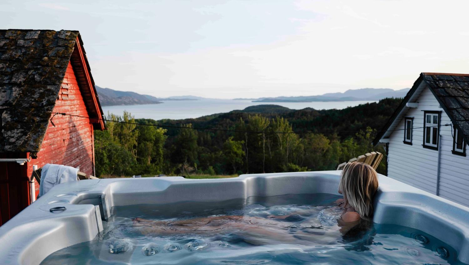Relaxing in an outdoor hot tub with panoramic Hardangerfjord views at Stigen Fjordlodge.