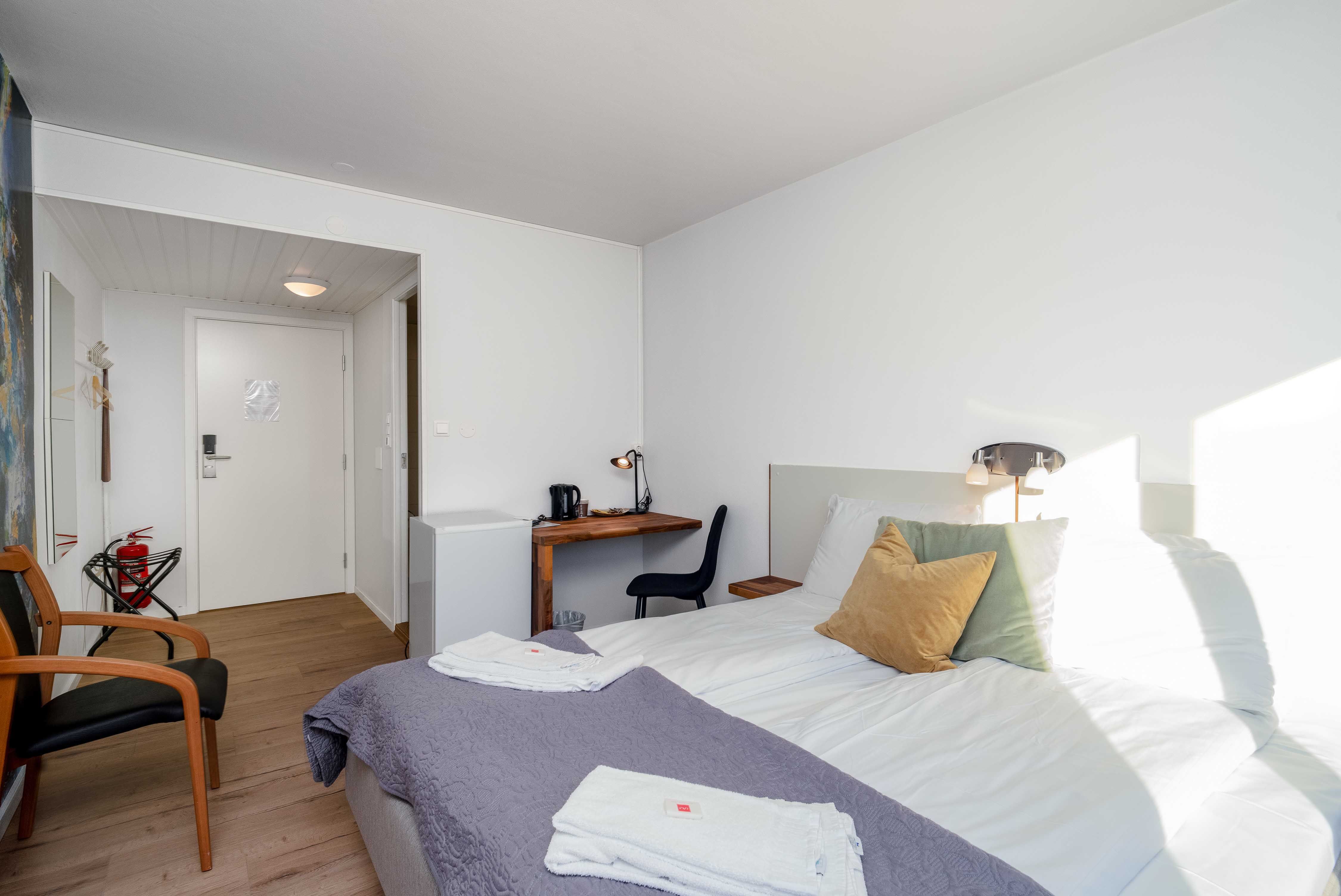 Hotellrom på Husnes Sentrum Hotell med skrivebord, stol og praktisk innreiing for både kvile og arbeid.