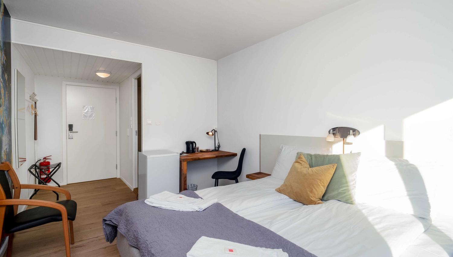 Hotel room at Husnes Sentrum Hotel featuring a desk, chair and functional design for both rest and work.