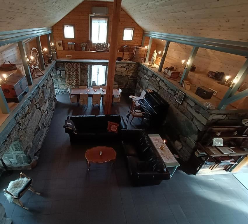 Orheimstunet in Nordfjord - View from a loft into a rustic room with stone walls, leather sofa, dining table, piano, and candlelight..