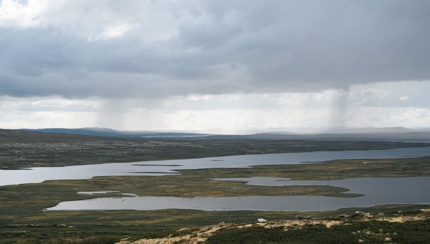 Viser et stort fjellvann under en overskyet himmel.