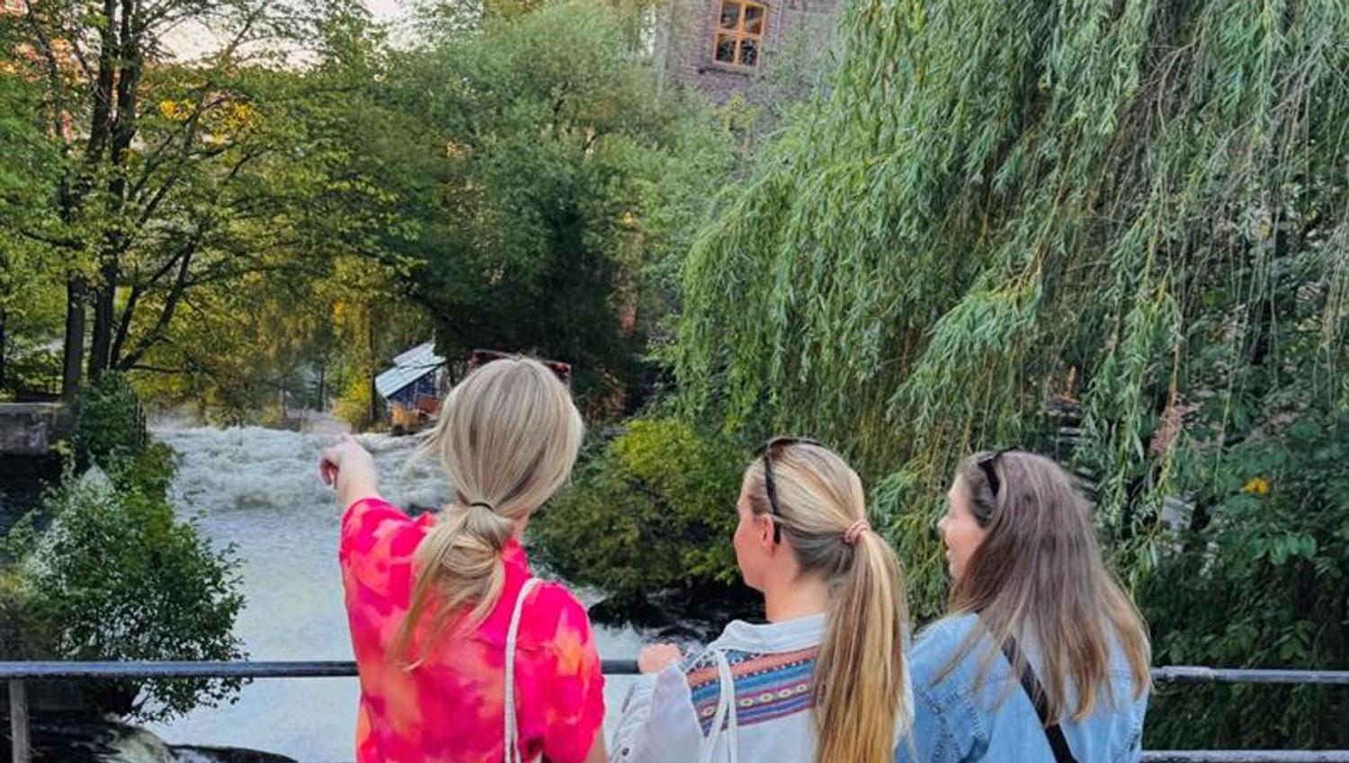 Three girls standing on a bridge watching over the Akerselva river