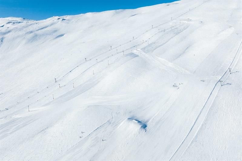 Sonnige Pisten und Skilifte im Røldal Skigebiet, umgeben von schneebedeckten Gipfeln.