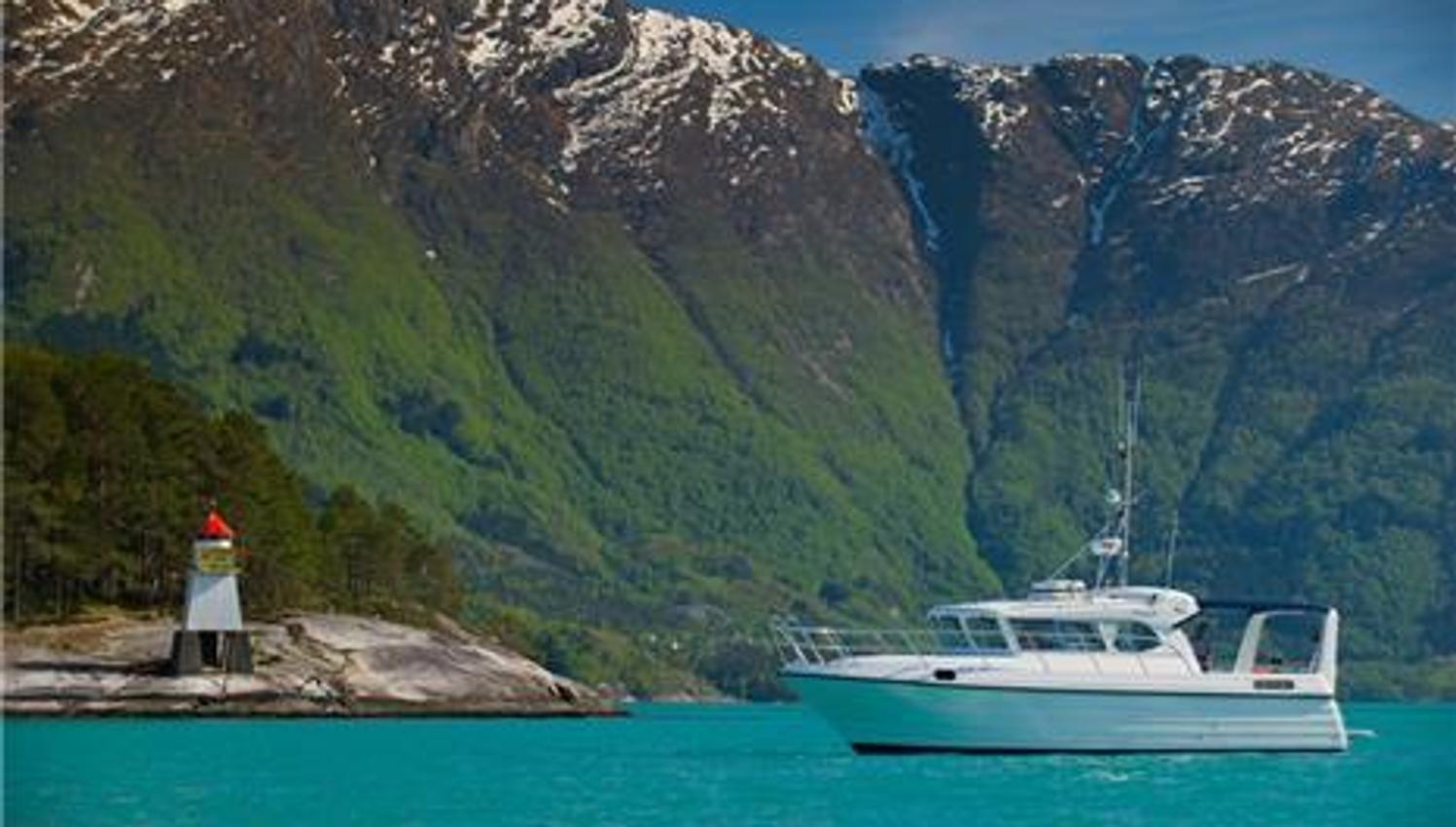 Pilagutt anchored in the Hardangerfjord, surrounded by majestic mountains and turquoise water. The ultimate fjord experience.