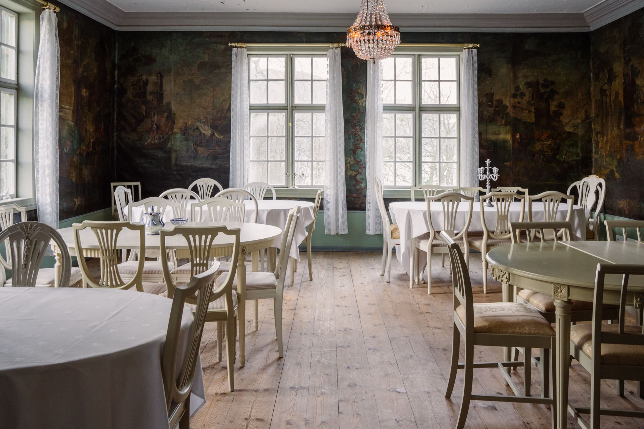 Bright dining room at Skrivergaarden with set tables and large windows, suitable for dinners and events.