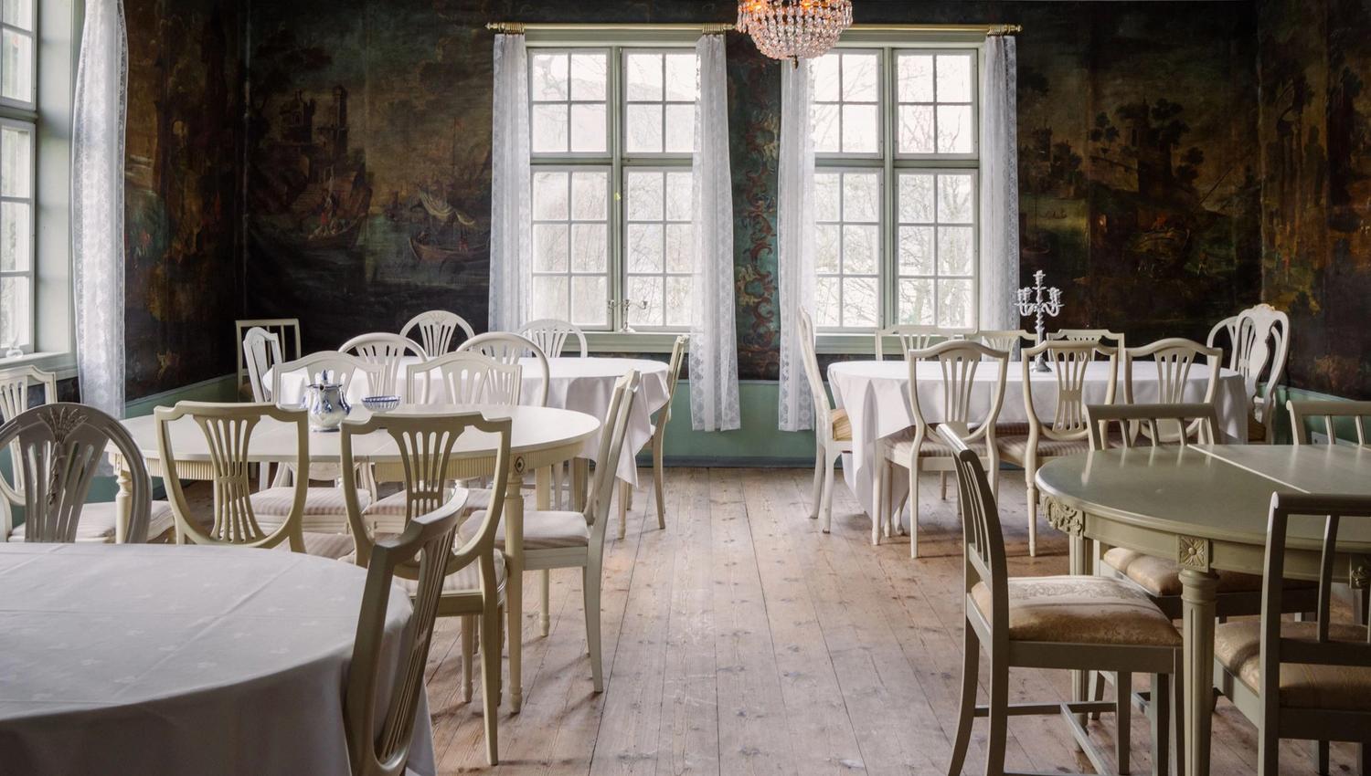 Bright dining room at Skrivergaarden with set tables and large windows, suitable for dinners and events.
