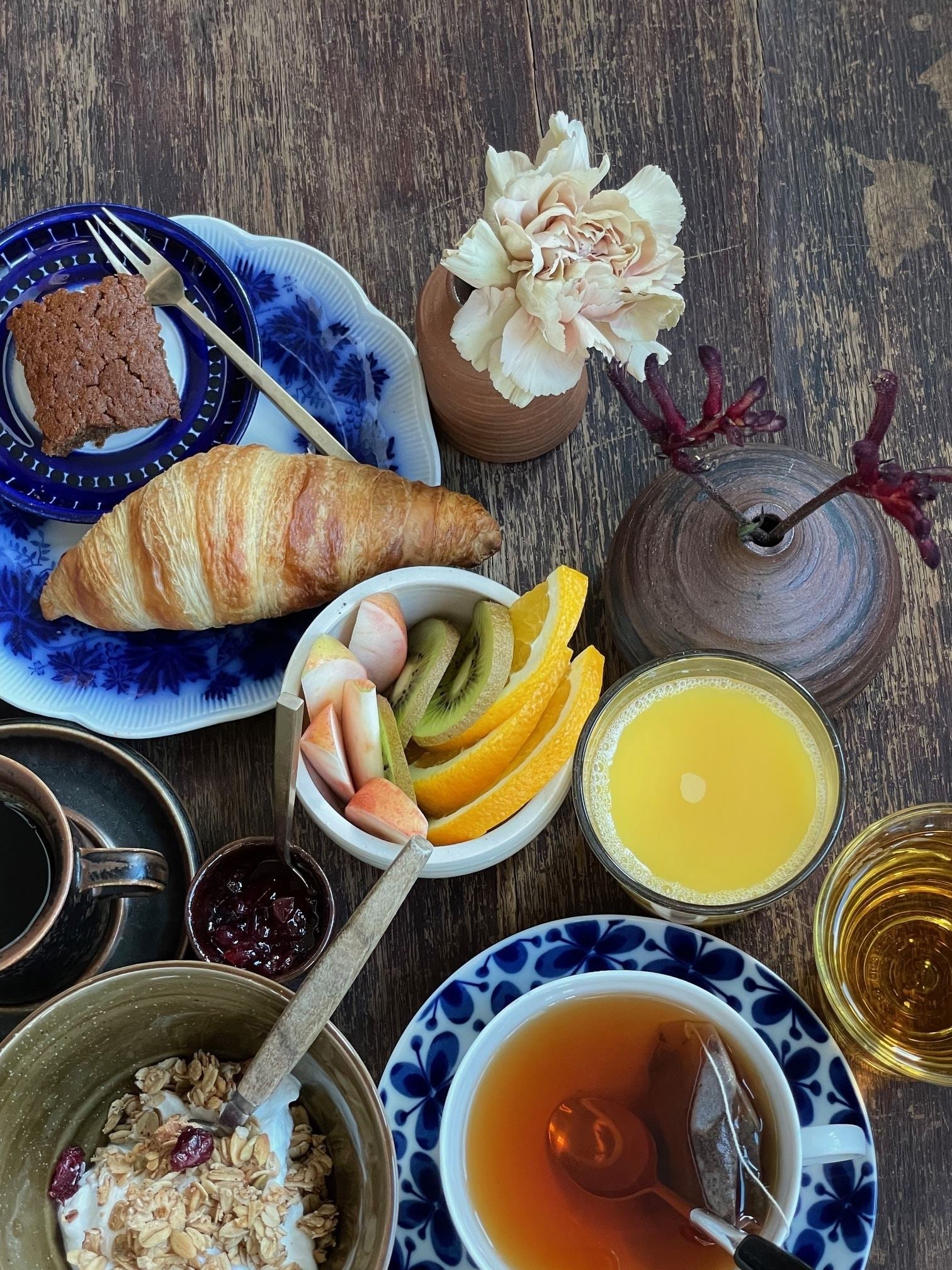 Frokostbord med croissant, kake, granola, frukt, juice og te