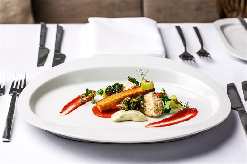 Detail photo of a dish on a white plate with cutlery and napkins next to it.