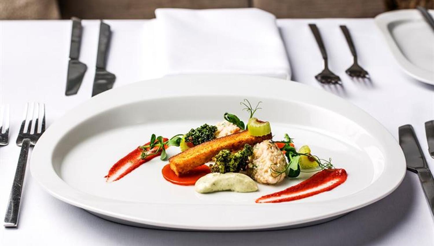 Detail photo of a dish on a white plate with cutlery and napkins next to it.