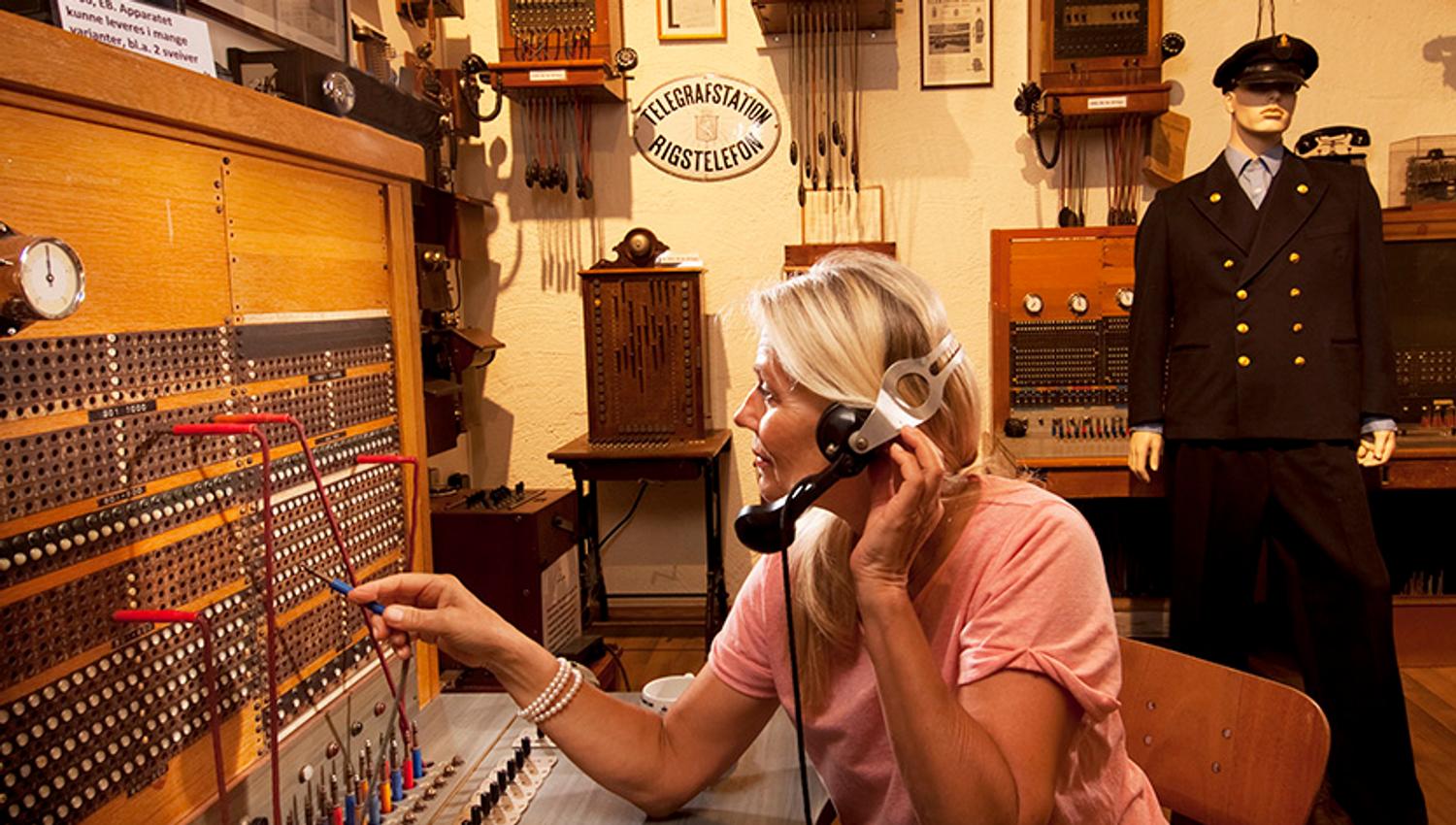 dame som sitter i en gammel telefonsentrale som utstilles på Z-museum i Nissedal
