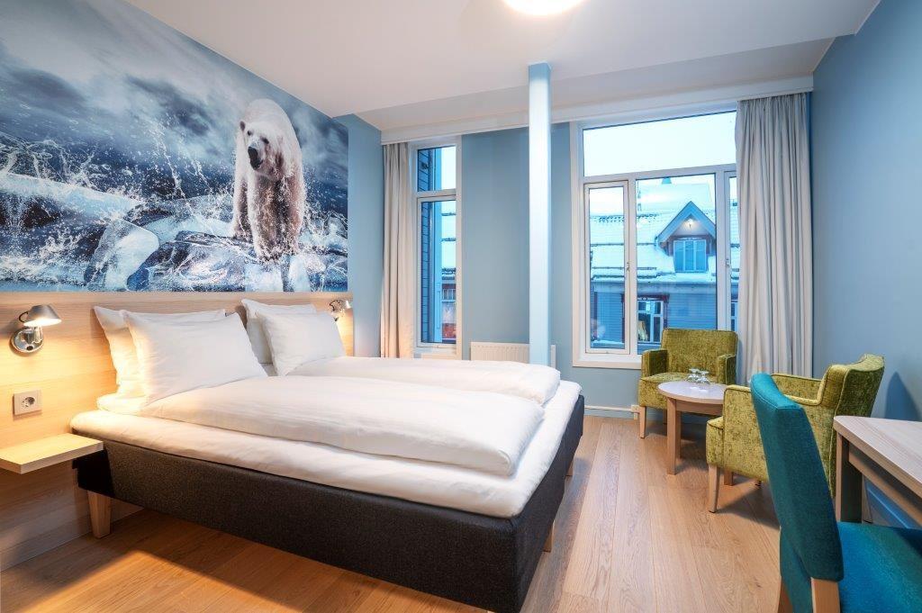 Modern room with a large bed, polar bear mural on the wall, and seating area.