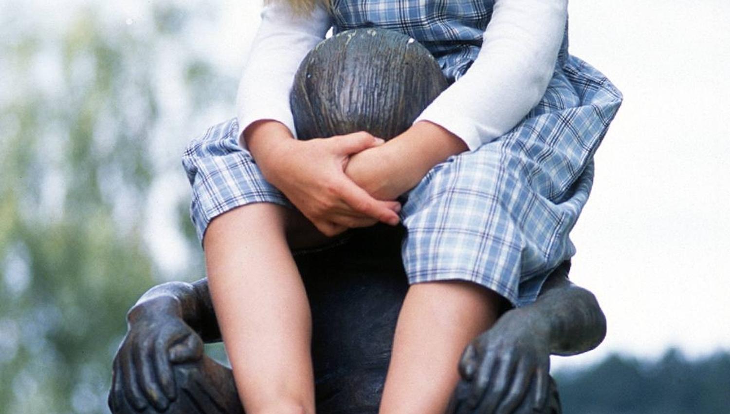 Smilende jente som sitter på en skulptur