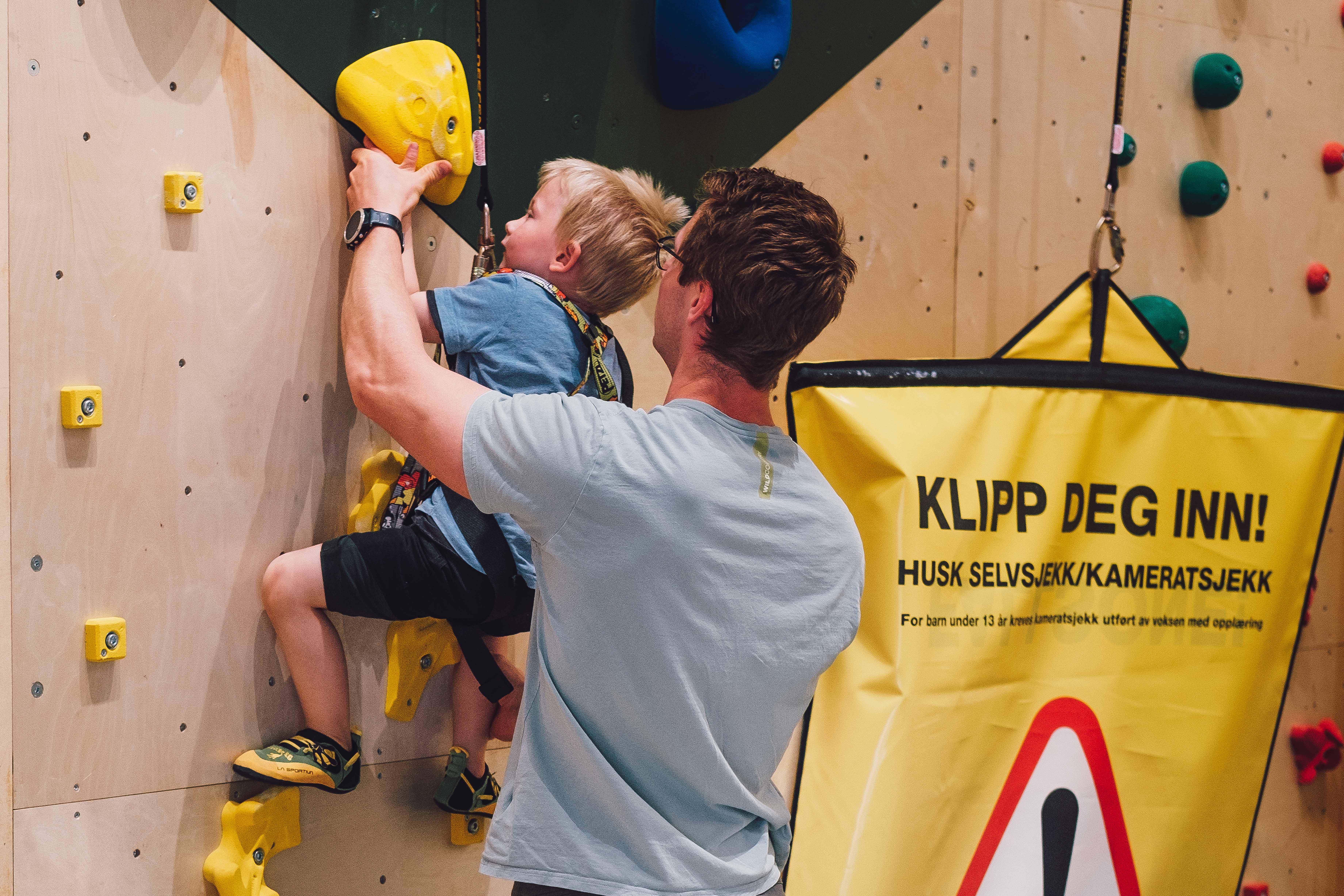 Father helping boy in climbing wall