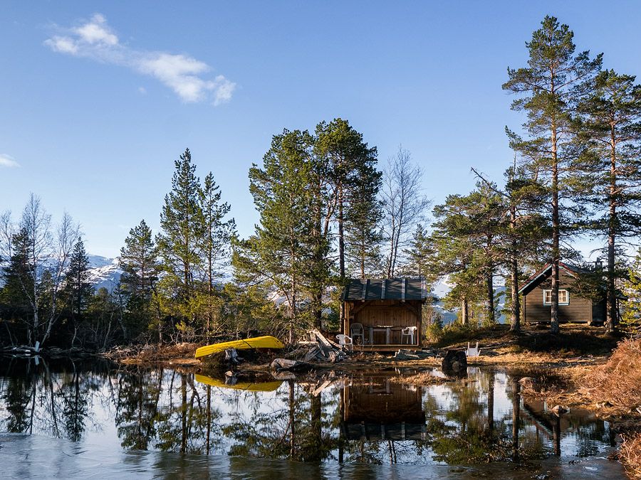 Frystetjørn in the evening sun with small cabins, calm water and a canoe – an idyllic and secluded hiking destination in Hardanger.