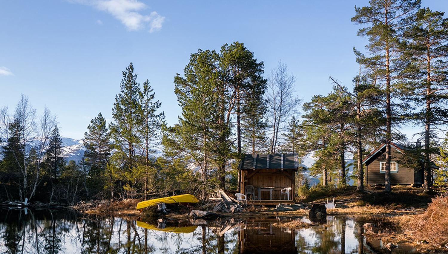 Frystetjørn in the evening sun with small cabins, calm water and a canoe – an idyllic and secluded hiking destination in Hardanger.