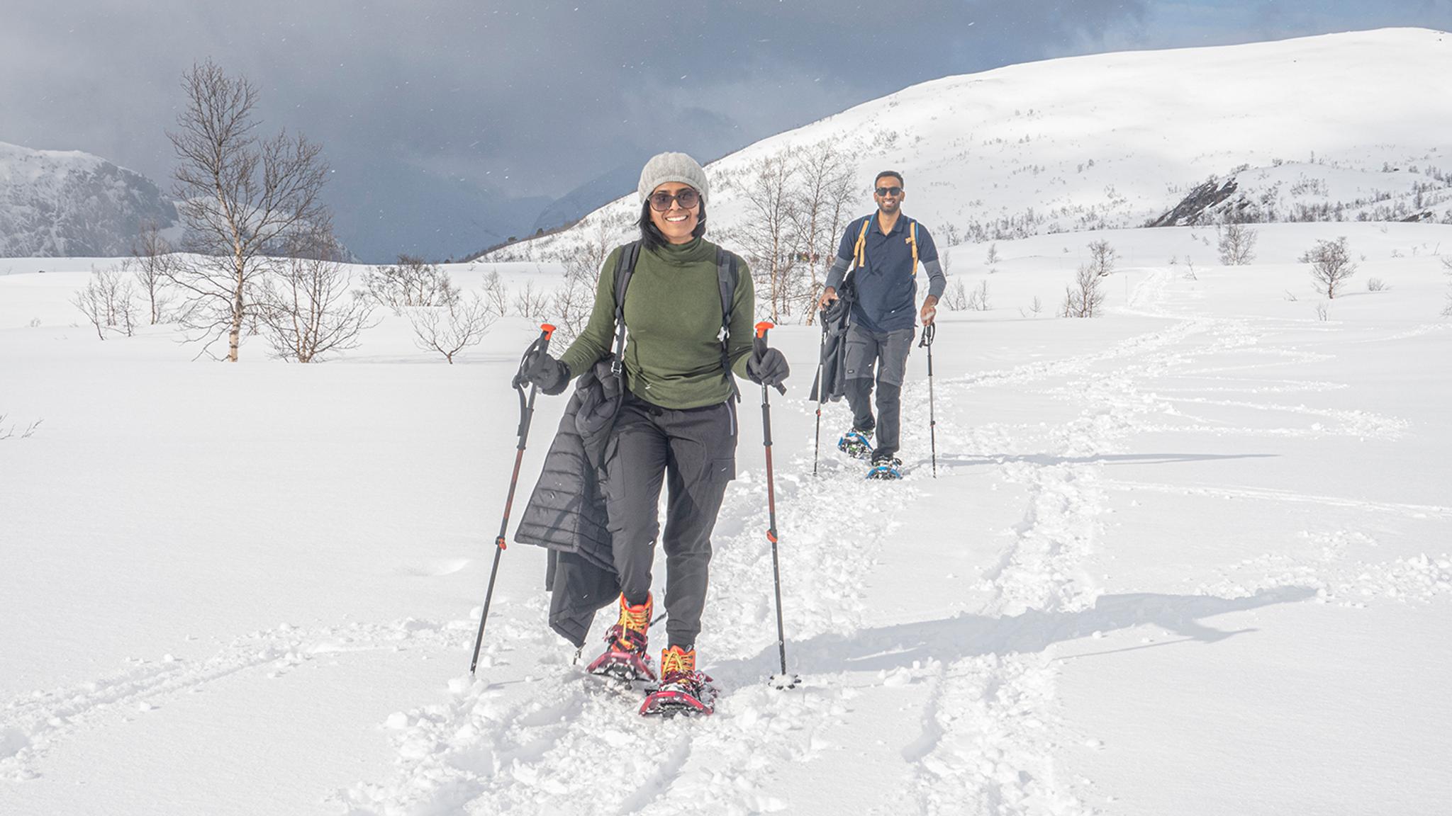 To glade turgåarar på trugetur i djup snø med vinterfjell i Hardanger.