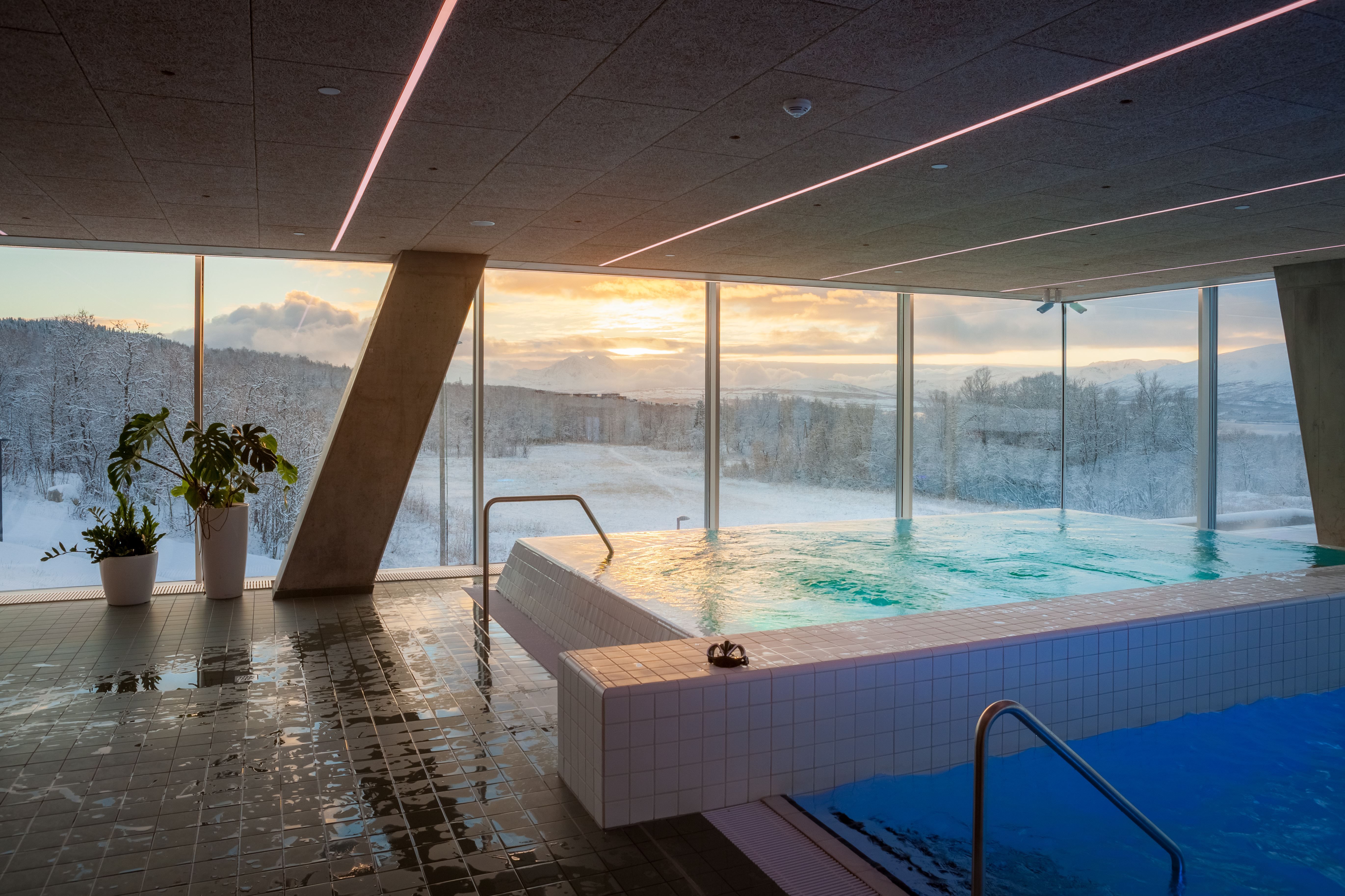 Indoor swimming pool with a view of snowy landscape and sunset