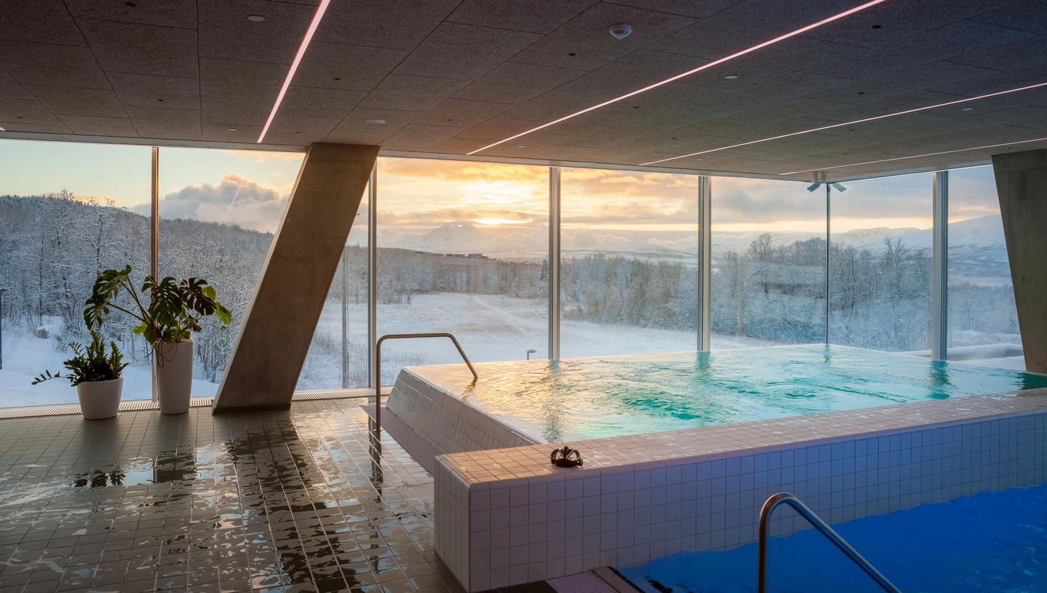 Indoor swimming pool with a view of snowy landscape and sunset