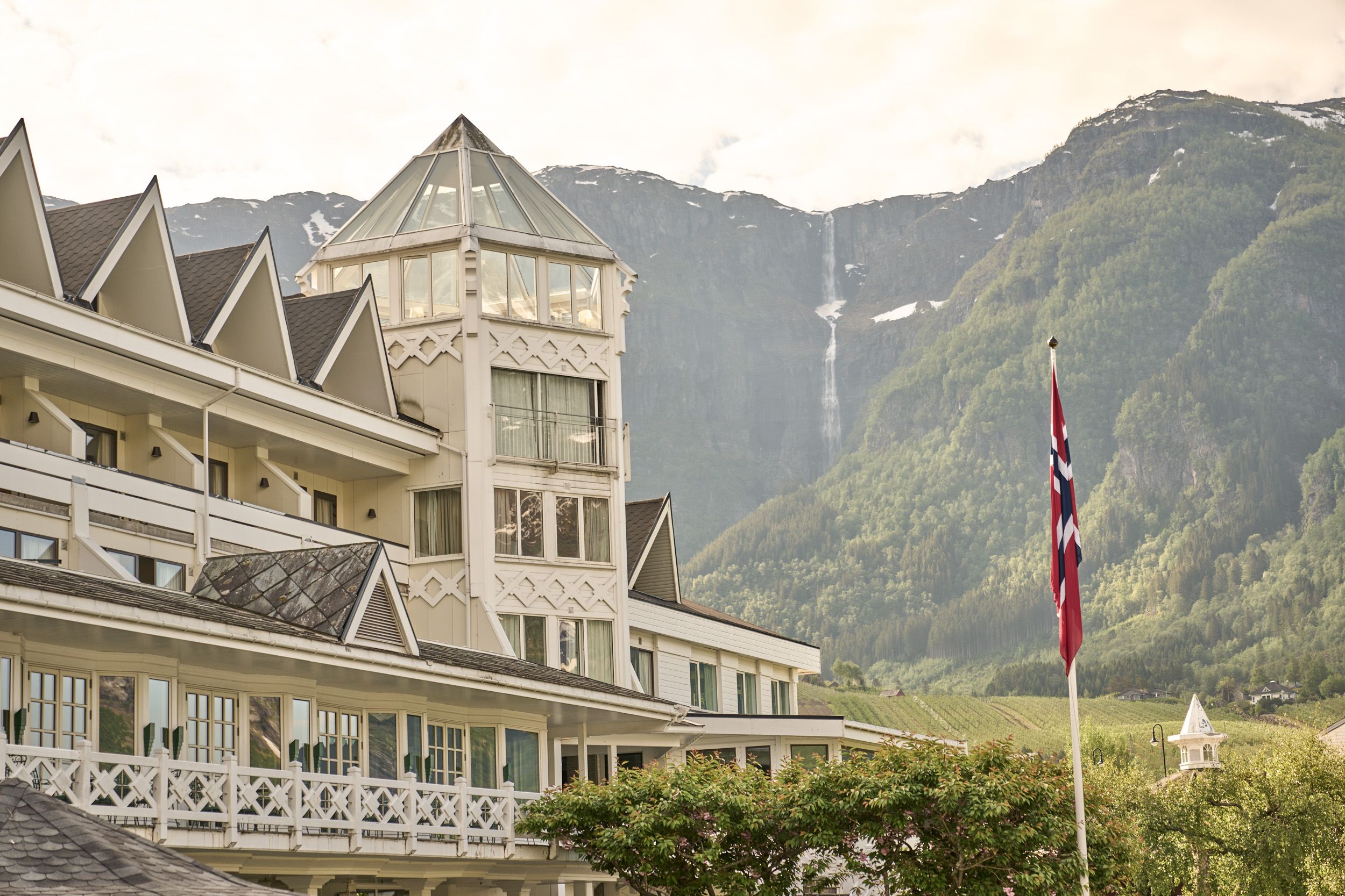 The iconic tower of Hotel Ullensvang with a dramatic waterfall cascading down the mountainside.