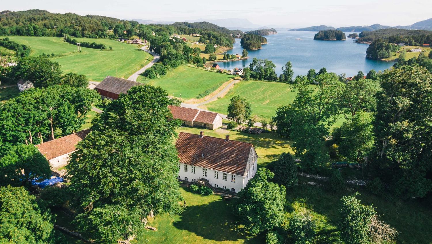 Dronebilete av Halsnøy Kloster med fjorden i bakgrunnen.