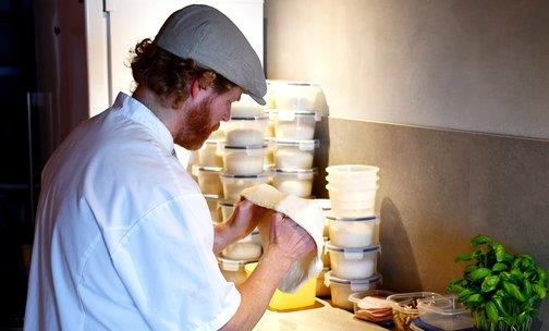 A man seen from the side, stretching out a pizza dough.