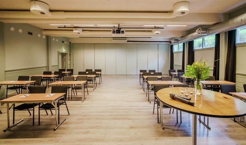 Lyst og romslig konferanselokale på Hankø Hotell & Spa, med bord og stoler, store vinduer og teknisk utstyr.