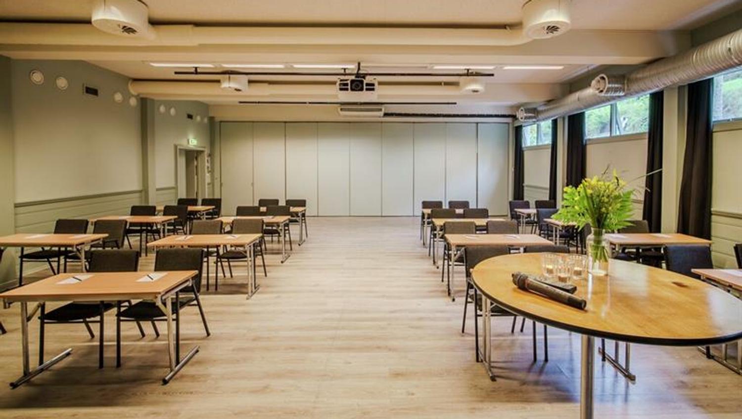 Lyst og romslig konferanselokale på Hankø Hotell & Spa, med bord og stoler, store vinduer og teknisk utstyr.