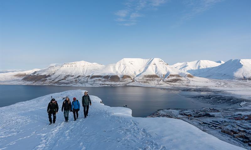 flere personer står på toppen av det snødekte fjellet