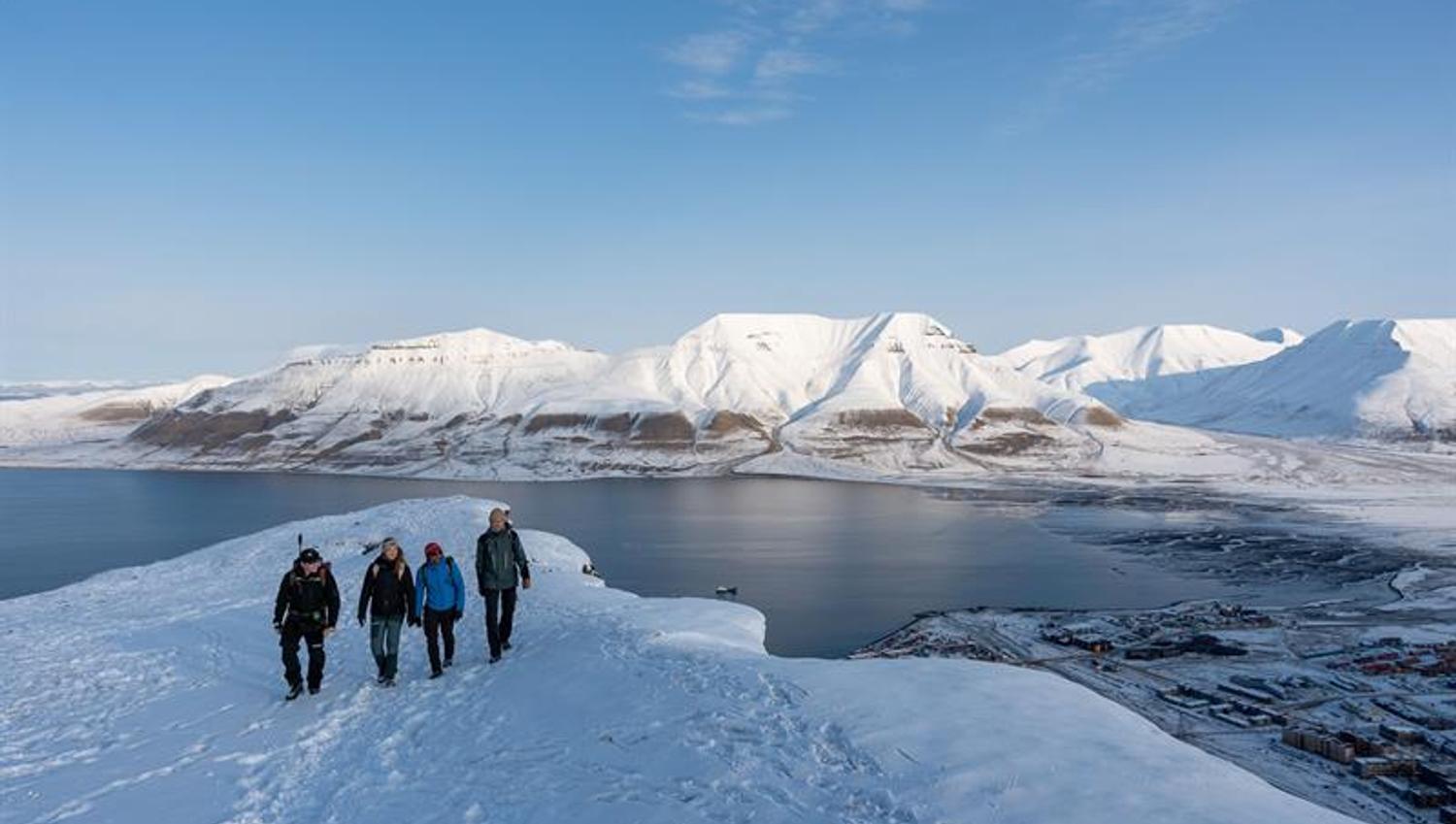 flere personer står på toppen av det snødekte fjellet