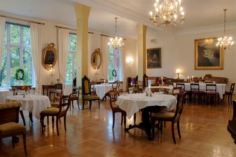 Elegant spisesal med bord med hvit duker og lysekroner i taket.