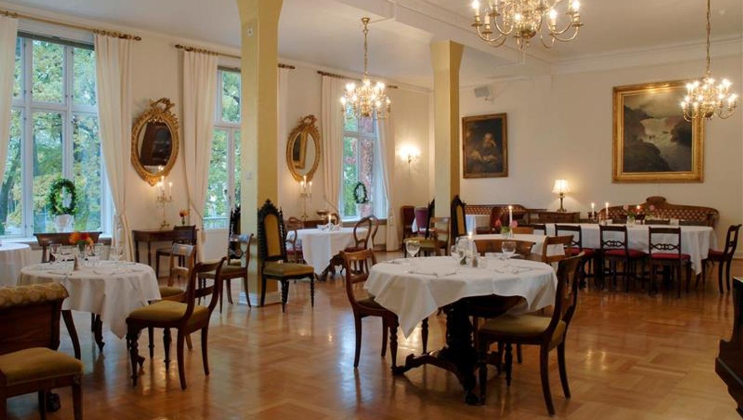 Elegant spisesal med bord med hvit duker og lysekroner i taket.
