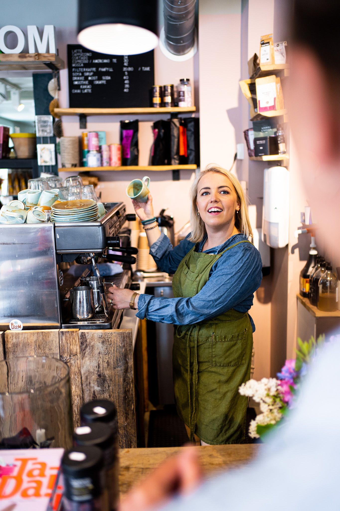 a woman making a coffee while talking with a customer 