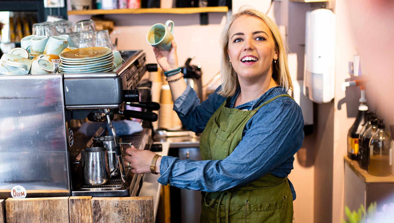 a woman making a coffee while talking with a customer