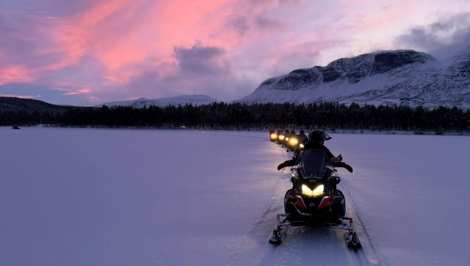 Snowmobile tour through the winter landscape of Skibotn Valley in the evening light