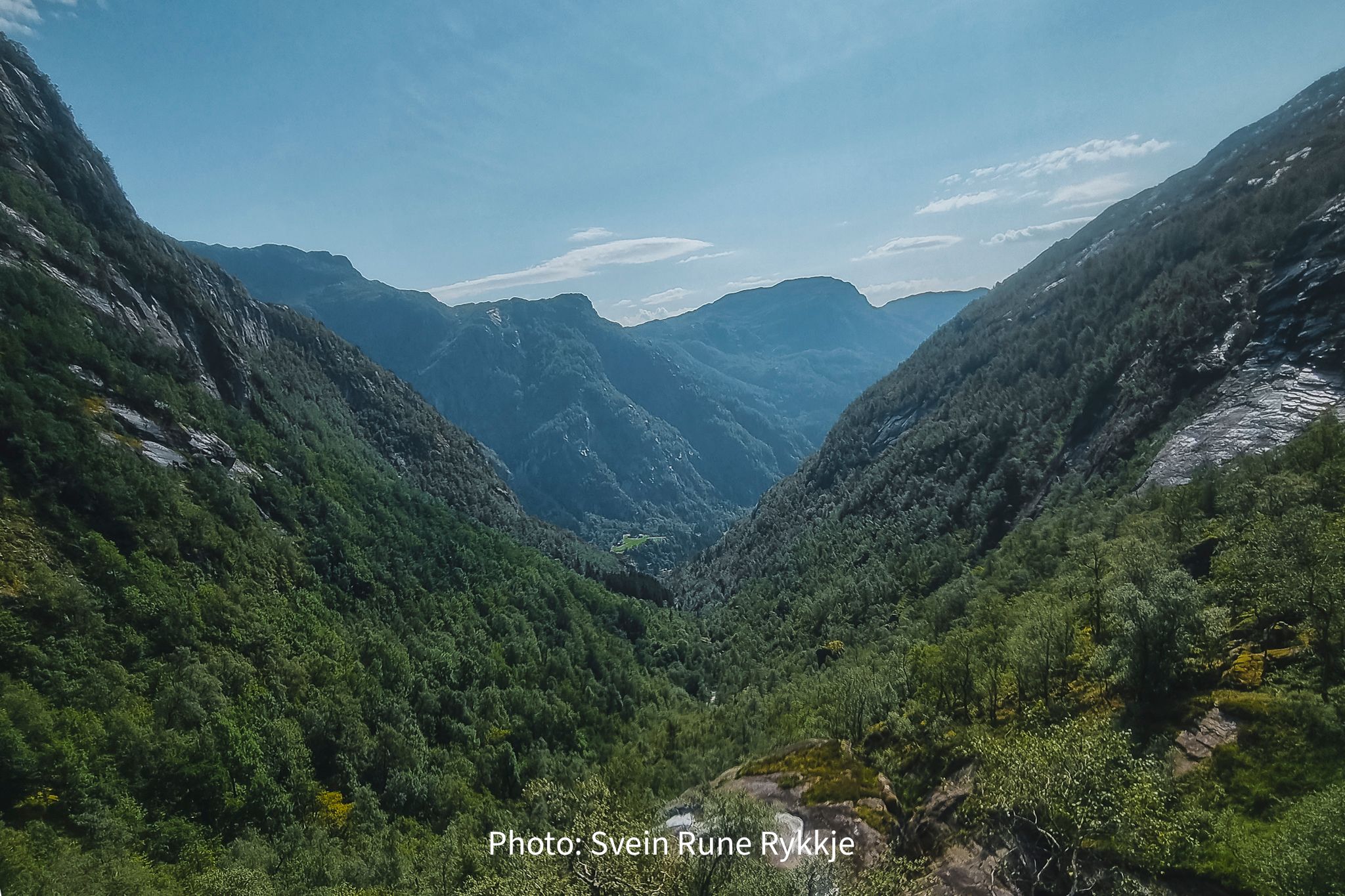 Lush green valley surrounded by steep mountains in Hardanger, Norway, ideal for hiking and nature lovers
