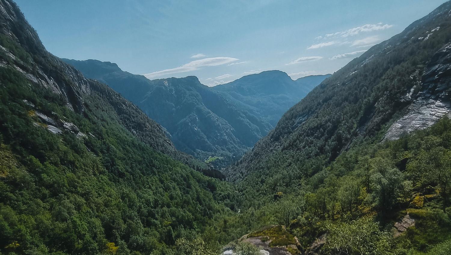 Lush green valley surrounded by steep mountains in Hardanger, Norway, ideal for hiking and nature lovers